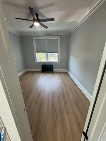 a view of a livingroom with wooden floor a ceiling fan and window