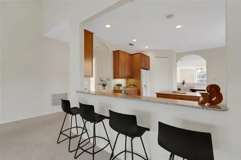 a large kitchen with kitchen island granite countertop a sink a counter top space and stainless steel appliances