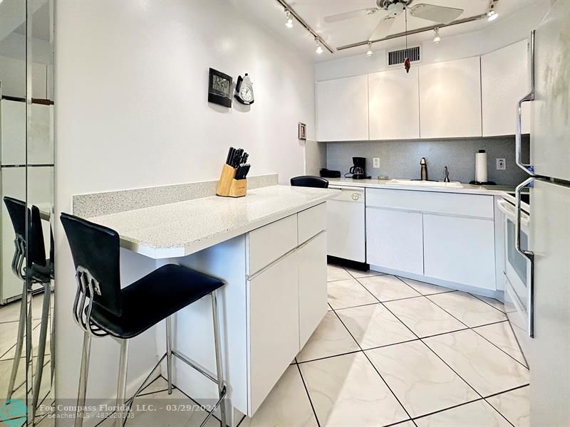 a kitchen with stainless steel appliances kitchen island a table chairs in it and white cabinets