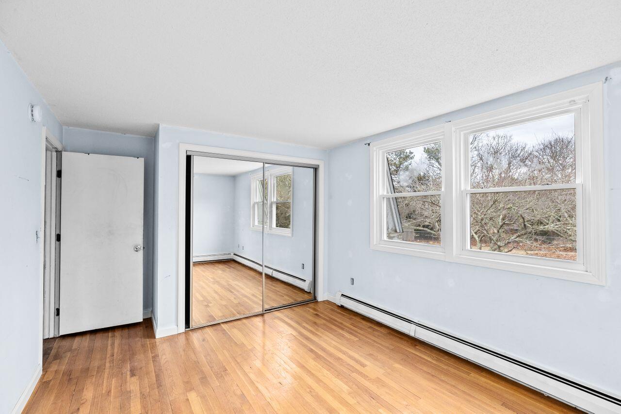 1460 Massasoit Road Eastham, MA 02642 - Photo 16 of 42 an empty room with wooden floor and windows