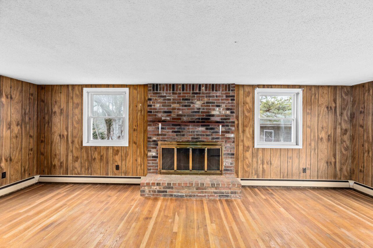 1460 Massasoit Road Eastham, MA 02642 - Photo 9 of 42 an empty room with wooden floor fireplace and windows