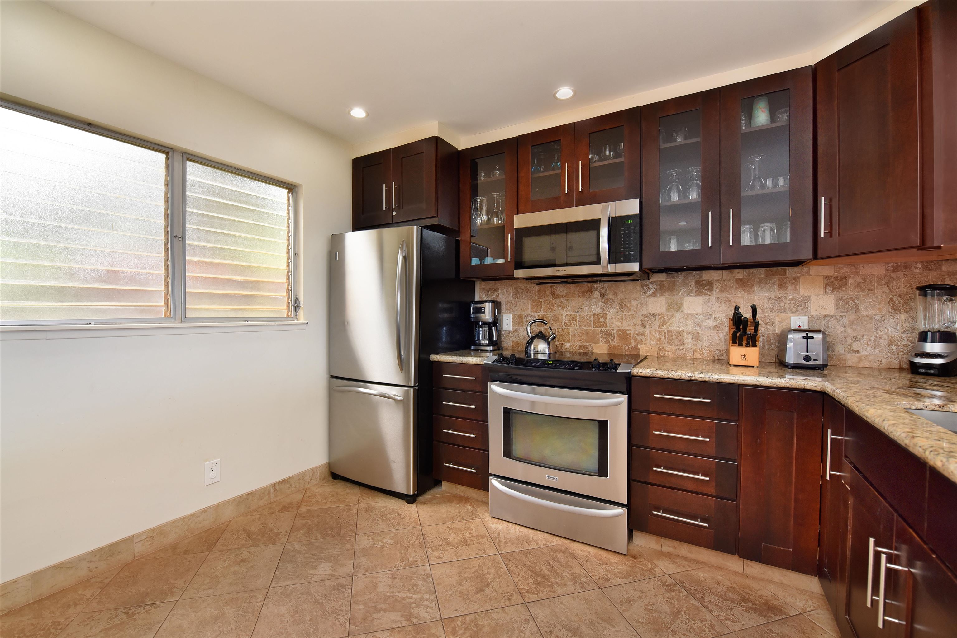 150 Puukolii Road, Unit 52 Lahaina, HI 96761 - Photo 7 of 50 a kitchen with stainless steel appliances granite countertop wooden cabinets a stove a refrigerator and a sink