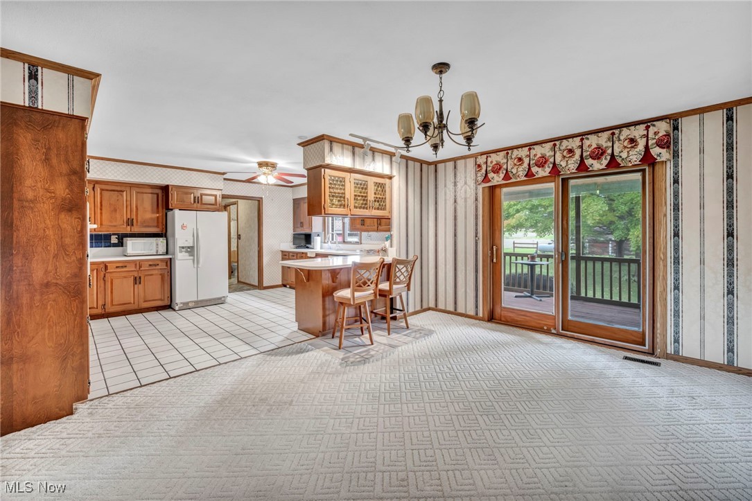 9184 Zimmerman Road Homerville, OH 44235 - Photo 23 of 50 Kitchen with a breakfast bar area, white appliances, ornamental molding, pendant lighting, and ceiling fan with notable chandelier