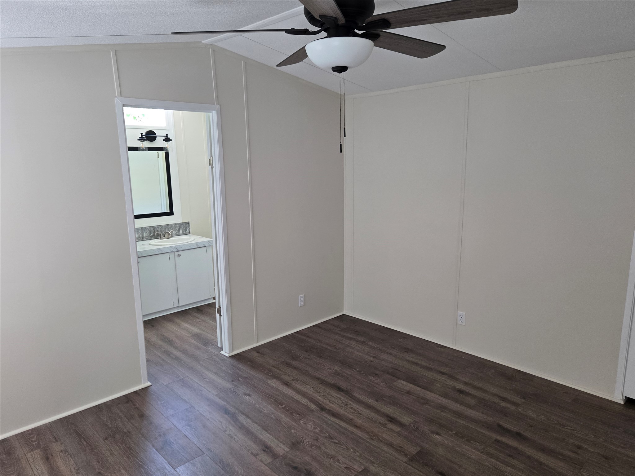2807 Lone Tree Road Victoria, TX 77901 - Photo 6 of 12 Room featuring wood-finish flooring, a ceiling fan with integrated lighting, and light-toned wall paneling
