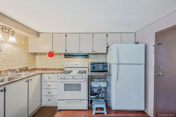 a kitchen with a white refrigerator a sink a stove and white cabinets