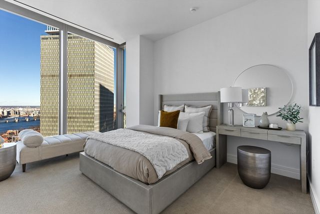 a bedroom with a bed table chair and a large window