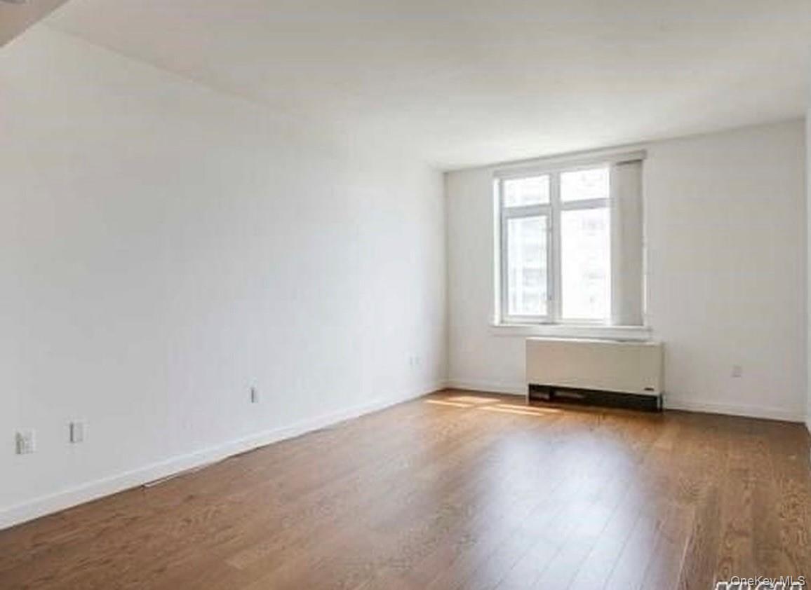 40-26 College Point Boulevard Queens, NY 11354 - Photo 7 of 10 an empty room with wooden floor and windows