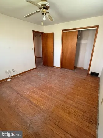 an empty room with wooden floor and hallway