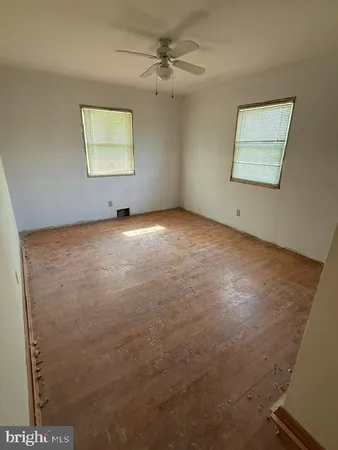 an empty room with windows and ceiling fan
