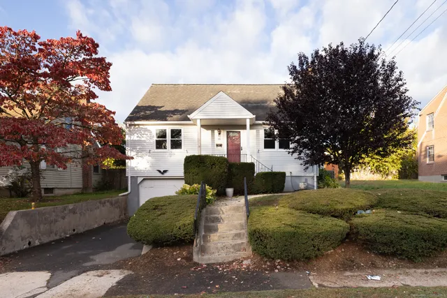 a front view of a house with a garden and trees