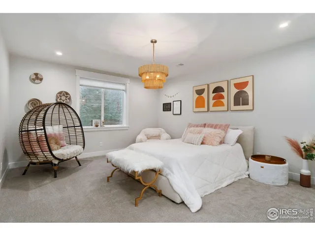 a living room with a bed furniture a chandelier and a window