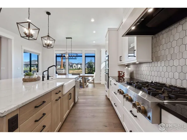 a large kitchen with stainless steel appliances granite countertop a stove a sink dishwasher and white cabinets with wooden floor