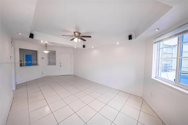 an empty room with chandelier fan and windows