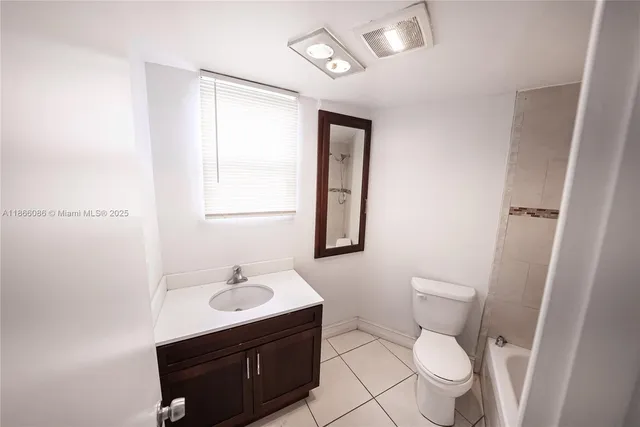 a bathroom with a toilet a sink a mirror and a window