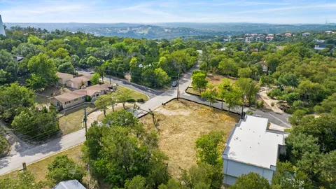 an aerial view of residential houses with outdoor space and trees all around