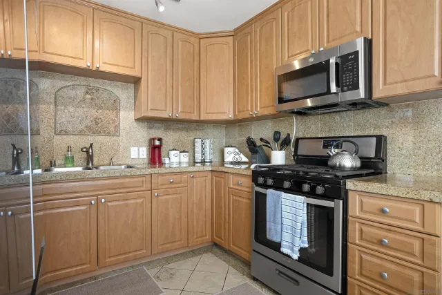 a kitchen with stainless steel appliances granite countertop white cabinets stove top oven and microwave