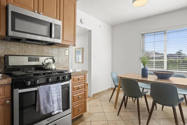 a kitchen with stainless steel appliances a stove a microwave a dining table and chairs