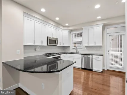 a kitchen with stainless steel appliances granite countertop a sink stove and microwave