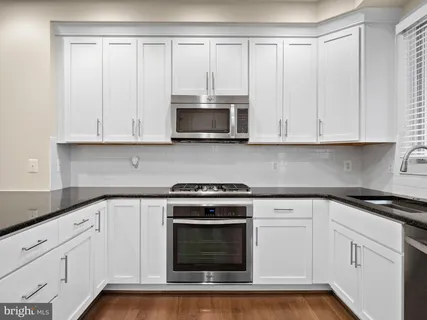 a kitchen with granite countertop white cabinets and stainless steel appliances