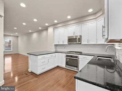 a kitchen with granite countertop white cabinets and stainless steel appliances