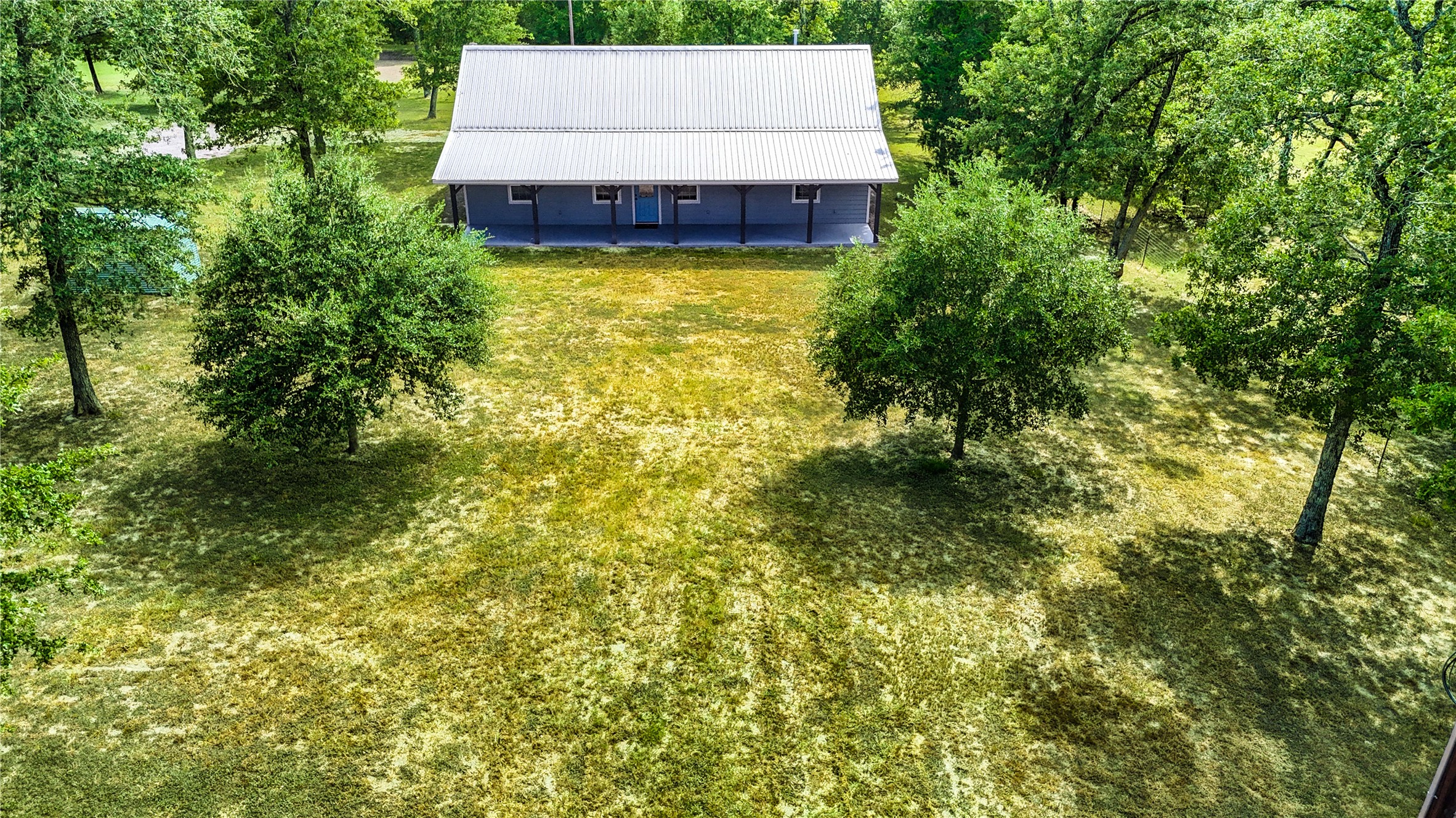 8805 Sun Oil Road Brenham, TX 77833 - Photo 50 of 50 Charming rural home with a spacious metal roof, nestled on a large, grassy lot surrounded by mature trees, offering serene privacy and natural beauty.