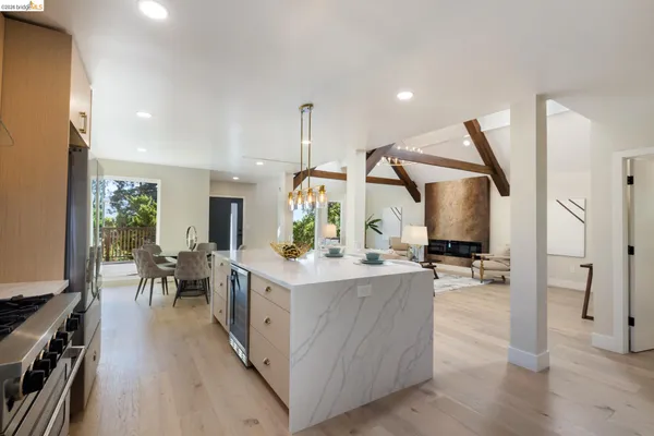 a view of a kitchen with kitchen island stainless steel appliances wooden floor dining table and chairs