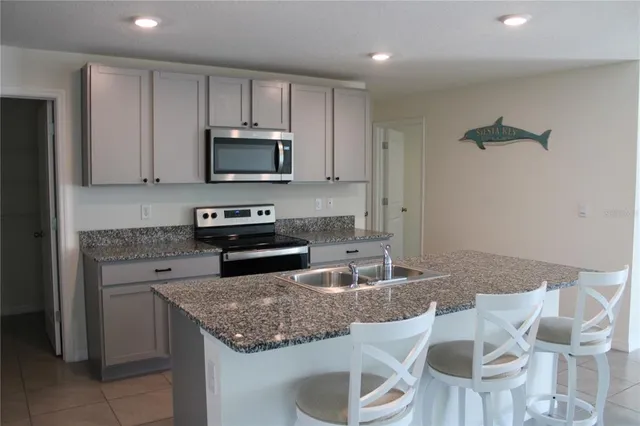 a kitchen with granite countertop stainless steel appliances a stove a sink a microwave a refrigerator and cabinets