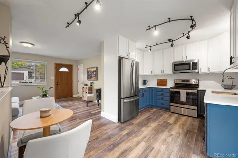 a kitchen with stainless steel appliances granite countertop a refrigerator a stove top oven a sink dishwasher a dining table and chairs with wooden floor
