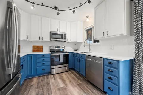 a kitchen with stainless steel appliances granite countertop a stove top oven a sink dishwasher and a refrigerator with wooden cabinets