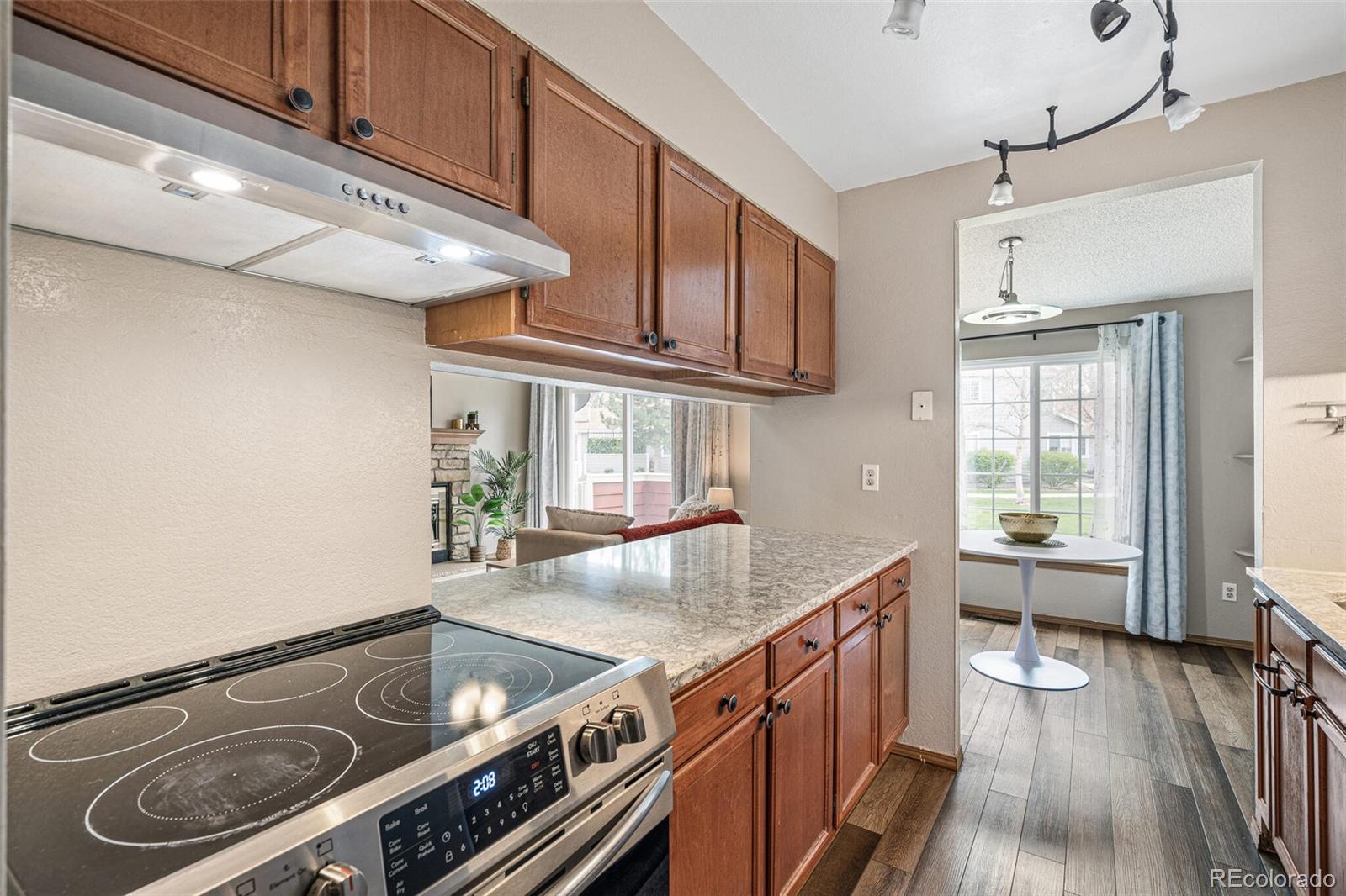 8424 Everett Way, Unit A Arvada, CO 80005 - Photo 12 of 25 a kitchen with granite countertop a stove and a wooden floors