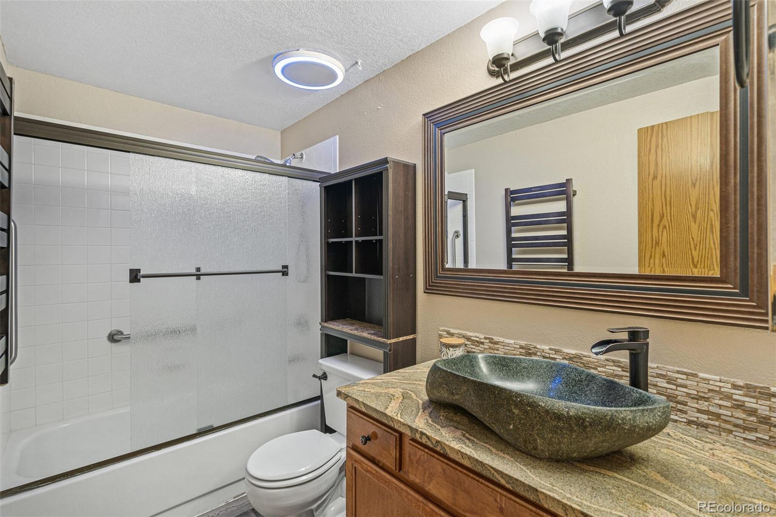 8424 Everett Way, Unit A Arvada, CO 80005 - Photo 17 of 25 a bathroom with a granite countertop sink toilet a mirror and shower