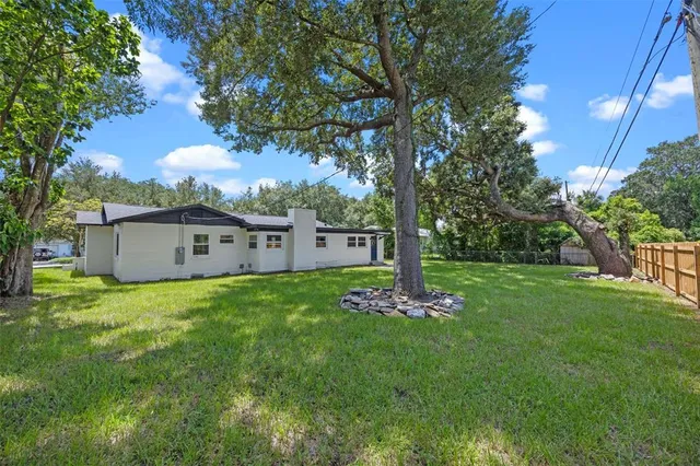 a view of a house with a big yard and large trees