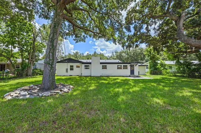 a view of a house with a big yard and large trees