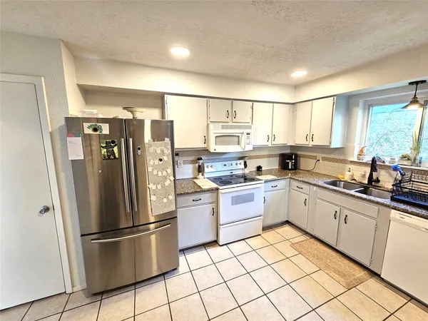 a kitchen with granite countertop appliances a sink a counter top space and cabinets