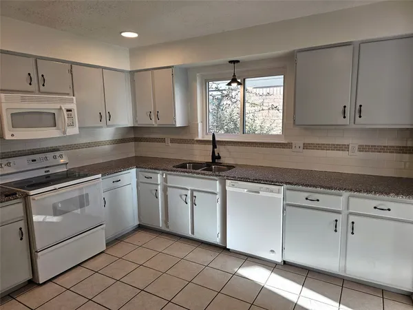 a kitchen with cabinets appliances a sink and a window