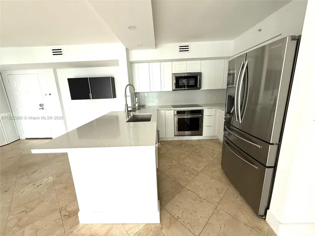 a view of a kitchen with a sink furniture a refrigerator and a fireplace