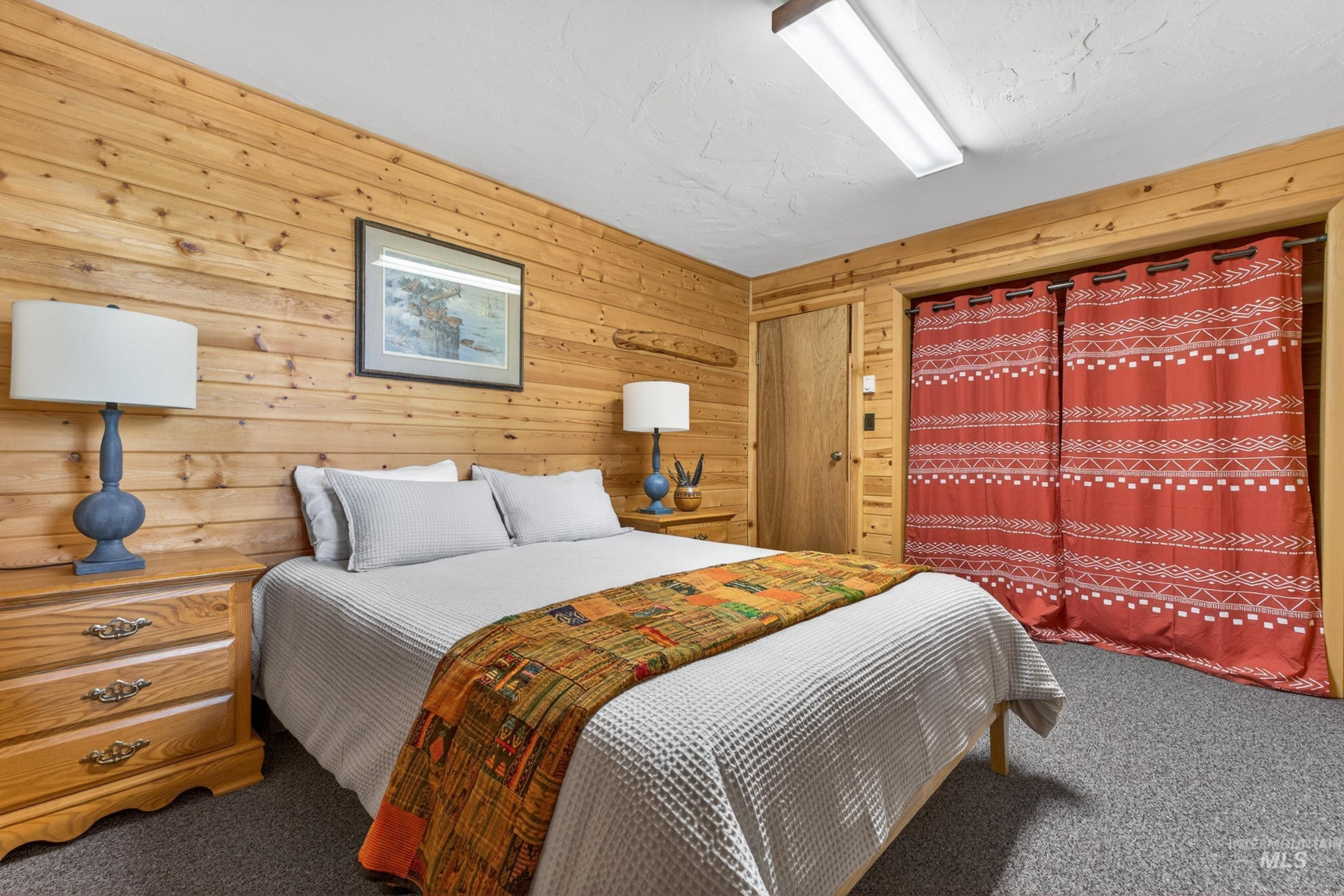 2339 West Mountain Road Donnelly, ID 83615 - Photo 15 of 37 Wood-paneled room featuring textured gray carpet, a solid wood door, and a built-in closet area with patterned fabric coverings