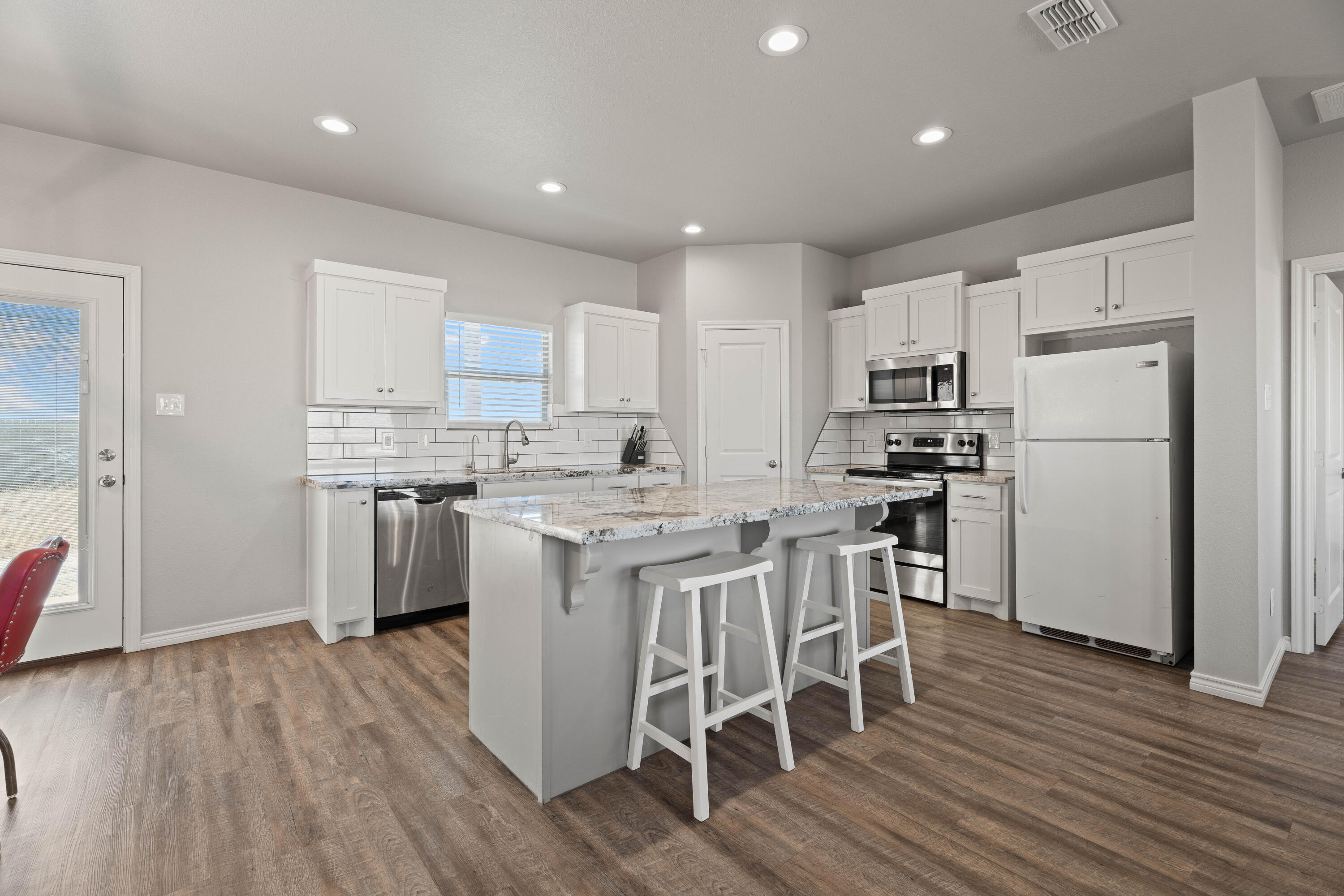 8907 County Road 6100 Shallowater, TX 79363 - Photo 6 of 24 a kitchen with a refrigerator a microwave oven a sink a dining table and chairs