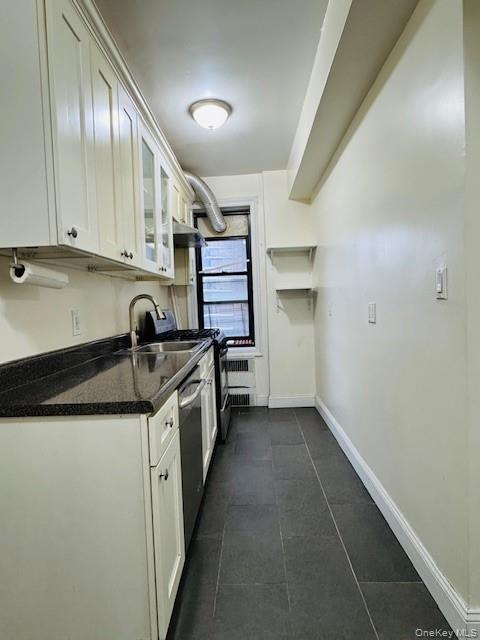 92-05 Whitney Avenue, Unit A27 Queens, NY 11373 - Photo 3 of 14 Kitchen featuring white cabinetry, glass insert cabinets, appliances with stainless steel finishes, and radiator