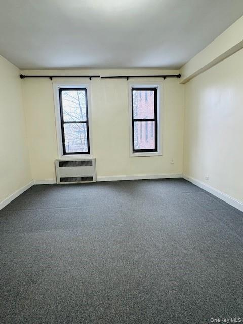 92-05 Whitney Avenue, Unit A27 Queens, NY 11373 - Photo 4 of 14 Spare room featuring plenty of natural light, radiator, and dark colored carpet