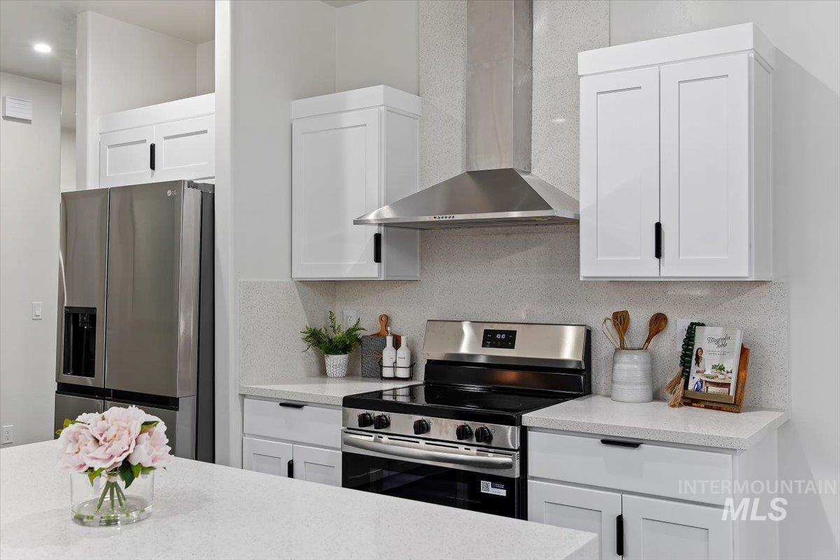 1189 Trail Crest Road Twin Falls, ID 83301 - Photo 11 of 44 Kitchen featuring wall chimney range hood, appliances with stainless steel finishes, white cabinets, and tasteful backsplash