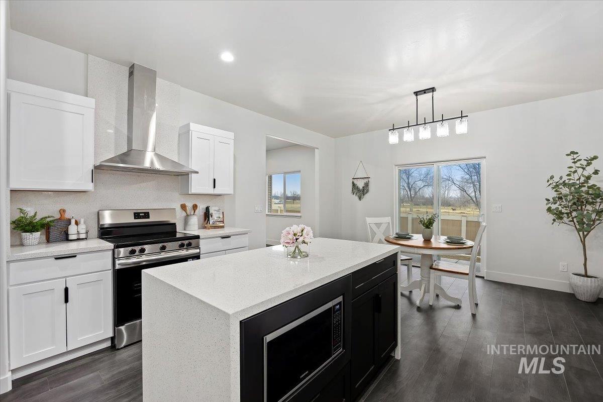 1189 Trail Crest Road Twin Falls, ID 83301 - Photo 13 of 44 Kitchen with stainless steel range with electric stovetop, wall chimney exhaust hood, decorative light fixtures, dark cabinets, and a center island