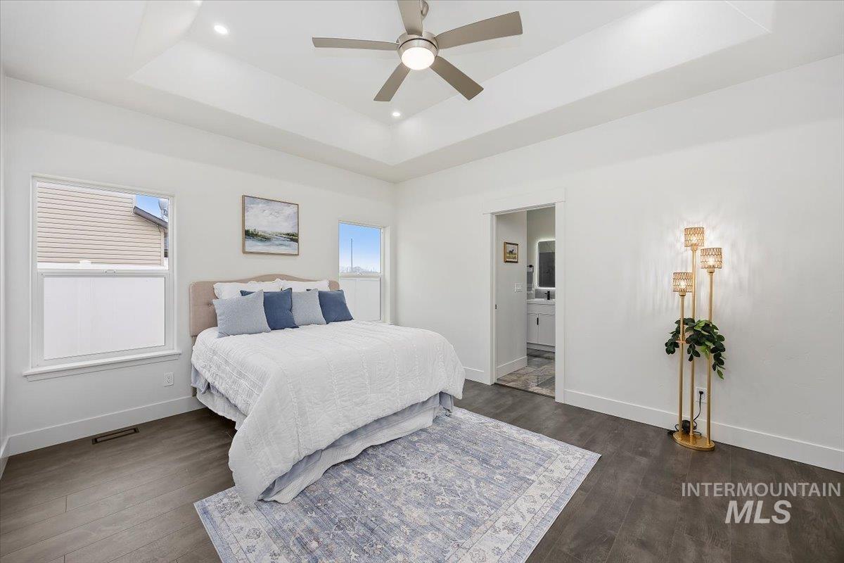 1189 Trail Crest Road Twin Falls, ID 83301 - Photo 18 of 44 Bedroom with a tray ceiling, a ceiling fan, connected bathroom, dark wood-type flooring, and recessed lighting