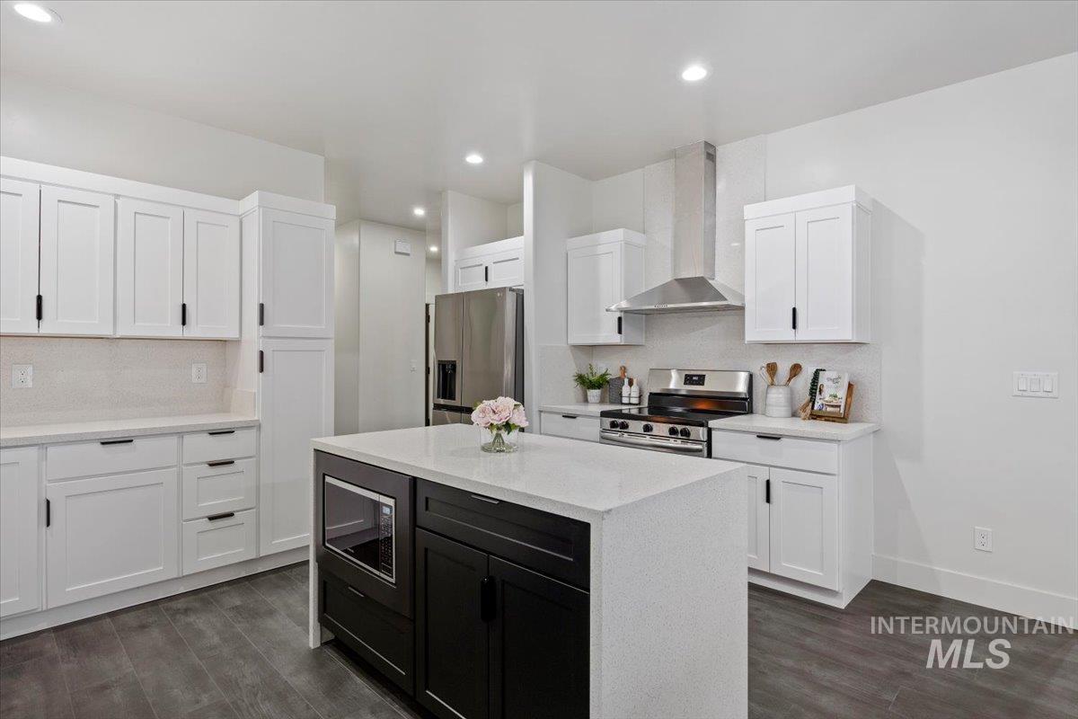 1189 Trail Crest Road Twin Falls, ID 83301 - Photo 10 of 44 Kitchen featuring light stone counters, wall chimney range hood, dark cabinetry, stainless steel appliances, and white cabinets