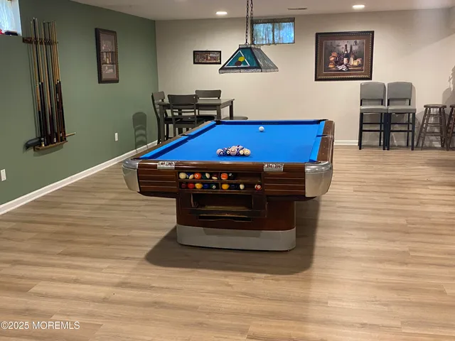 a room with wooden floor pool table and windows