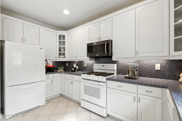 a white kitchen with stainless steel appliances and white cabinets