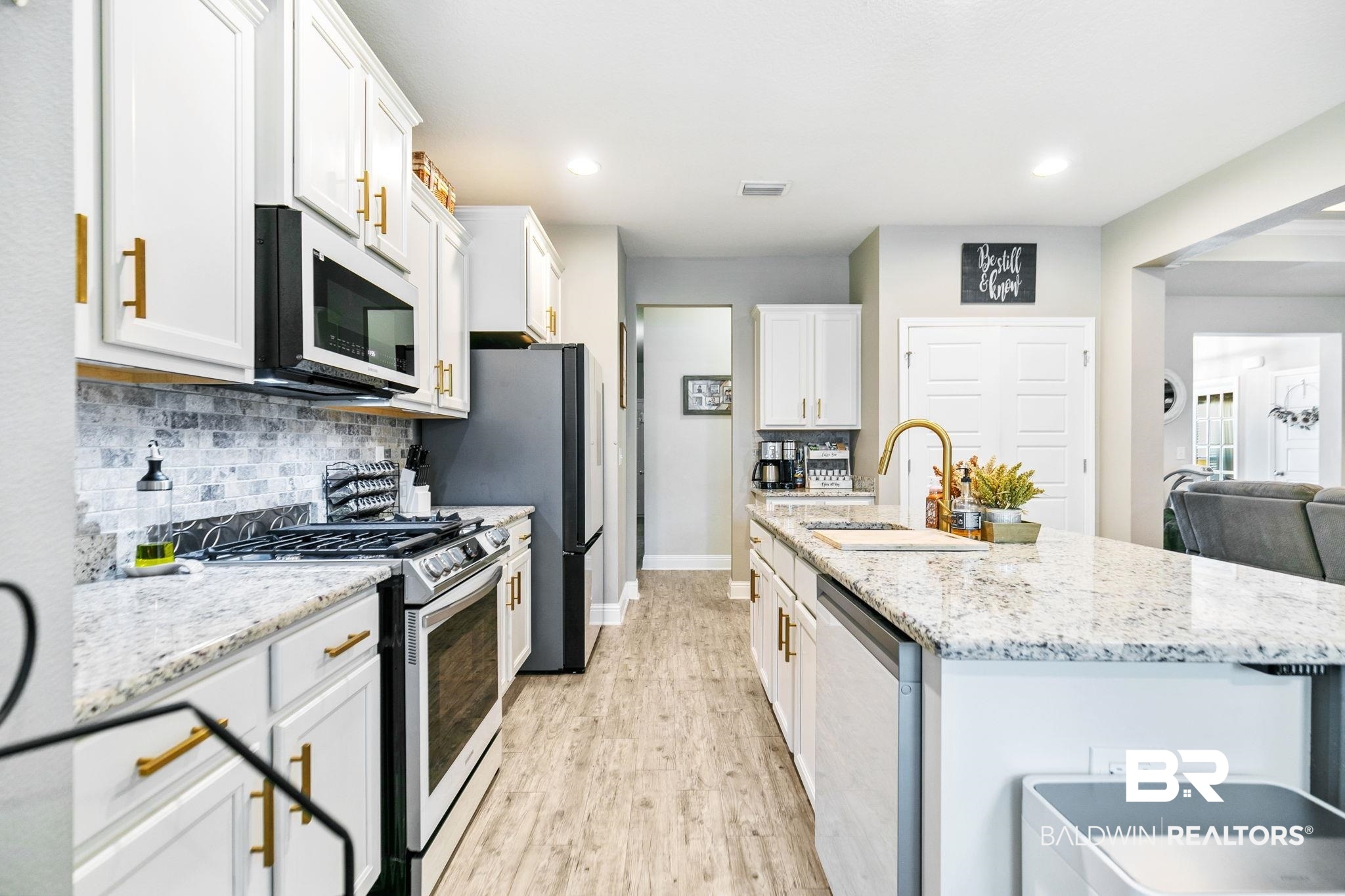 31402 Hoot Owl Road Daphne, AL 36527 - Photo 11 of 43 Kitchen featuring white cabinetry, sink, light hardwood / wood-style floors, appliances with stainless steel finishes, and backsplash