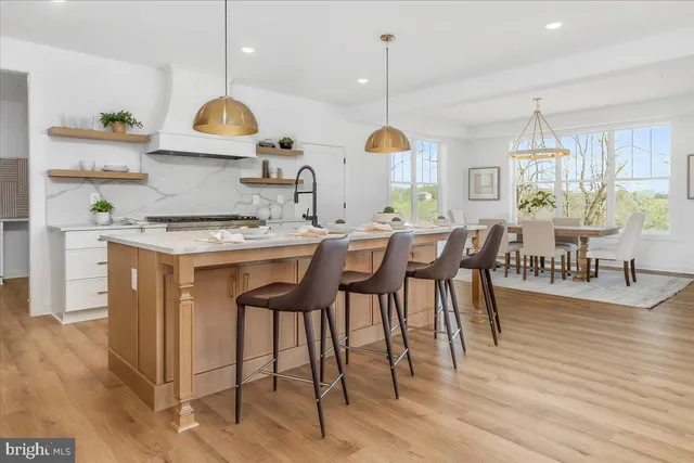 a kitchen with stainless steel appliances granite countertop a stove a sink a oven a dining table and chairs with wooden floor