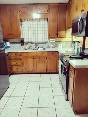a kitchen with stainless steel appliances granite countertop a sink a stove and a wooden cabinets