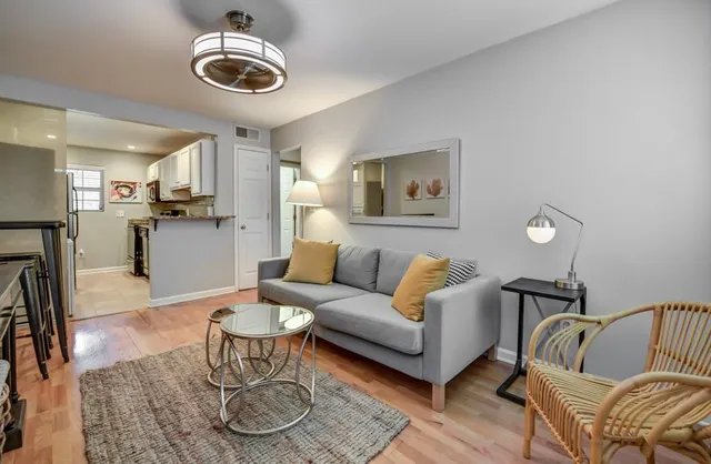 a living room with furniture kitchen view and a chandelier